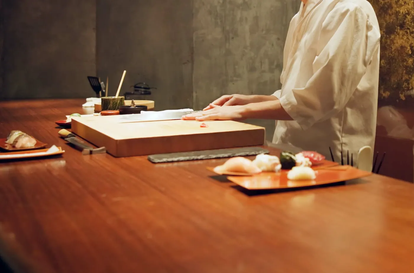 A piece of nigiri being formed by hand at the counter